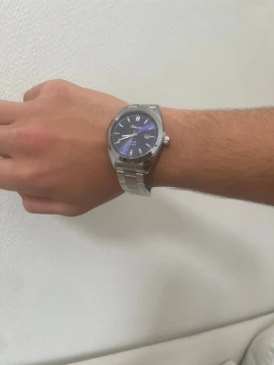 Blå klocka +plus Klockarmbandsverktyg - Snygg klocka  blå urtavla och silverfärgat länkarmband i metall. Klassisk rund form och tydliga indexmarkeringar. Kommer med originalask och extra länkar. Perfekt accessoar för att lyfta din stil.