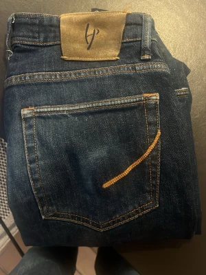 Handpicked Jeans - Säljer ett par mörkblå jeans från Handpicked med klassisk femficksdesign och raka ben. Jeansen har snygga kontrastsömmar och insidan är dekorerad med randigt tyg och rosor. Perfekta för dig som gillar stilrena men unika detaljer. Superfet och nische.