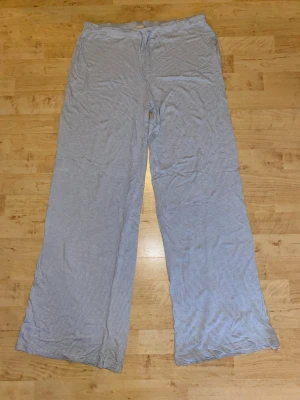 Blåvitrandiga pyjamasbyxor L - Mysiga pyjamasbyxor från 157 i storlek L. Byxorna är blåvitrandiga med dragsko i midjan och raka, lösa ben. Perfekta för chillkvällar hemma. Tillverkade i mjukt och lätt material som känns skönt mot huden.