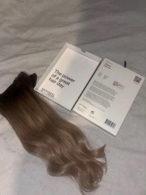  balayage löshår från Rapunzel - Säljer ett clip-on löshår från Rapunzel of Sweden i en snygg brun balayage med mörkare botten och ljusare längder. Håret är vågigt och ger ett naturligt intryck. Perfekt för dig som vill ha längre och fylligare hår på nolltid.