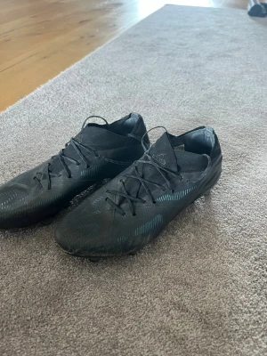 Svarta Adidas fotbollsskor - Säljer ett par svarta Adidas fotbollsskor med snörning och låg profil. Det är nemesis och det har ett par år på nacken, har en liten slitning vid ena tån annars felfria och sköna skor. Lite stora därav försäljningen.