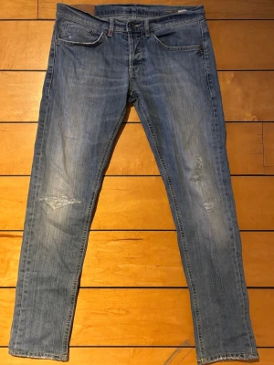 Dondup George jeans i blå tvätt W33 - Dondup George jeans i blå tvätt.  Storlek W33. Midja ca 42 cm liggande mått. Ytterben ca 102 cm.  Snygg slim passform och skön stretch. Jeansen är i fint använt skick med naturligt slitage som ger en snygg look.  D-emblemet på ena bakfickan saknas, men det påverkar varken passform eller användning.  Hör gärna av dig om du vill ha fler bilder eller mått.