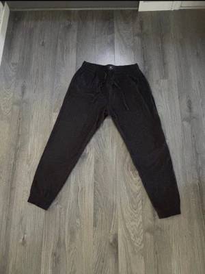 Svarta mjukisbyxor från H&M - Svarta mjukisbyxor från H&M med regular fit. Byxorna har resår i midjan med dragsko och muddar vid bensluten. Perfekta för chill dagar eller när du vill ha det extra bekvämt. Klassisk och enkel design som funkar till det mesta.