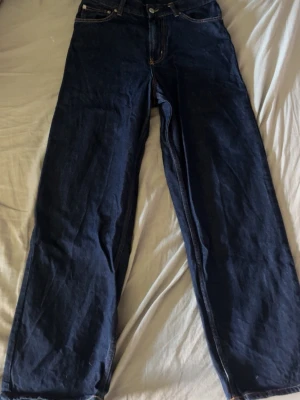 Mörkblå Sweet SKTBS jeans - Säljer ett par mörkblå jeans från Sweet SKTBS med raka ben och stor gul text på baksidan. Jeansen har klassisk femficksdesign och är tillverkade i kraftigt denimtyg. Perfekta för dig som vill sticka ut med streetwear-stil.