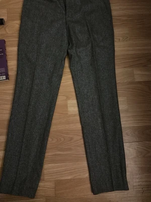 Grå kostymbyxor Tiger of Sweden - Snygga grå kostymbyxor från Tiger of Sweden i klassisk rak modell. Tillverkade i ett mjukt och stilrent tyg som passar perfekt till en dressad look. Byxorna har pressveck och diskreta fickor för en clean och modern känsla. Aldrig använda. 
