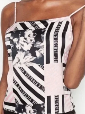  Victoria's Secret pyjamas - Säljer ett linne från Victoria's Secret med tunna axelband. Toppen har patchworkmönster i svart, vitt och ljusrosa med blommor och logotyptryck. Materialet känns mjukt och svalt, perfekt för chillkvällar eller sommarens varma nätter.