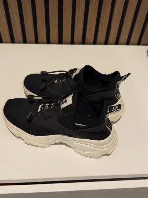 Svarta chunky sneakers Steve Madden - Snygga chunky sneakers från Steve Madden i svart mesh och syntet med vita, tjocka sulor. Skorna har svarta snören, vita detaljer och branding på plösen och hälen. 