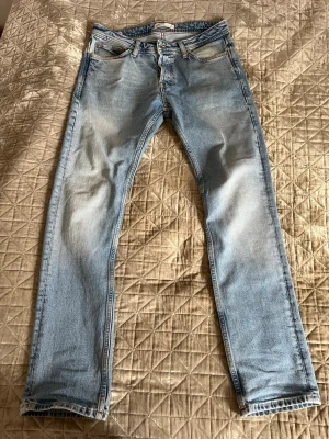 Ljusblå raka jeans från jack & Jones  - Säljer ett par ljusblå jeans från jack & Jones. Jeansen har snygga slitningar och tvättade detaljer framtill och baktill. 