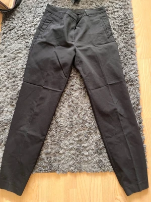 Svarta kostymbyxor med smal passform - Snygga svarta kostymbyxor med smal passform och klassisk design. Byxorna har snedställda fickor fram och är tillverkade i ett mjukt material som känns bekvämt hela dagen. Perfekta till en stilren look.