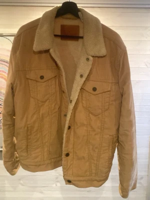 Beige jeansjacka  - Säljer en beige jeansjacka från levi’s med mysigt teddyfoder och krage. Klassisk modell med två bröstfickor med lock och knappar framtill. Jackan har en avslappnad passform och är perfekt för dig som vill ha en cool och bekväm look.