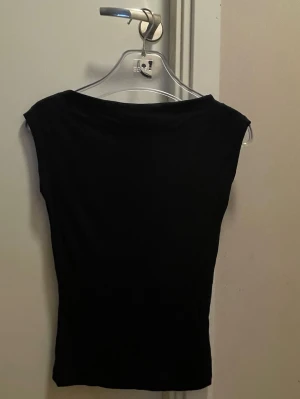 Svart ärmlös topp från Nelly XS - En enkel och stilren svart topp från Nelly i storlek XS. Toppen är ärmlös och har en smickrande, tight passform. Perfekt att matcha med jeans eller kjol för en clean look.
