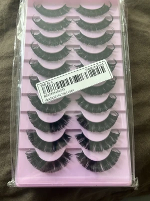 Svarta volymfransar i multipack - Säljer ett set med flera par svarta lösögonfransar i volymmodell. Fransarna har en böjd form och sitter i en rosa plastförpackning. Perfekta för dig som vill ha fylliga och dramatiska fransar. Materialet är syntetiskt.