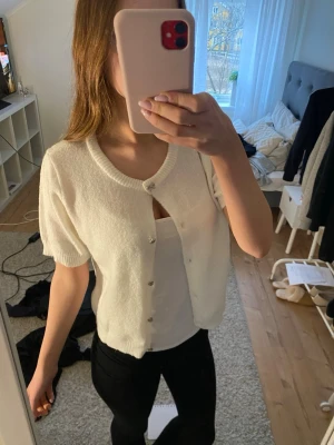 Supergullig kortärmad kofta - Söt vit kofta med korta ärmar och rund halsringning. Koftan har silvriga knappar framtill och är gjord i ett mjukt, stickat material, storlek 170💗