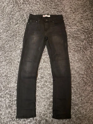 Svarta jeans från Levi's - Säljer ett par svarta skinny jeans från Levi's med klassisk femficksdesign och diskret slitning på låren. Jeansen har en smal passform och är tillverkade i stretchigt denim för extra komfort. Nästan helt nya har bara använt dem ca tre gånger. Kan diskutera pris och det är bara fråga om det finns några frågor!