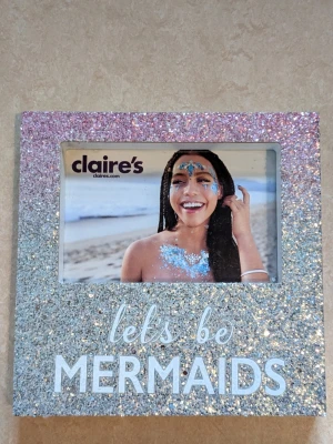 RAM från claire's - RAM från claire's med texten let's be MERMAIDS. RAMEN har aldrig använts. På två ställen på ramen saknas lite vit färg bifogar 2 bilder  HELT OANVÄND RAM. Prislappen finns kvar på ramen.