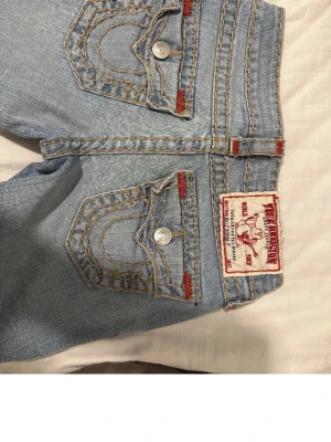 True Religion Low Waist Jeans - ✨PRIS GÅR ATT DISKUTERA VID SNABB AFFÄR✨    Säljer ett par lågmidjade jeans från True Religion som är straight leg, dom är ljusblå med unika detaljer och synliga sömmar, som ger den lilla extra effekten på hela outfiten! Verkligen ett par av mina favorit jeans, men säljer då dom tyvärr blivit för små!! Använda några gånger, men ser ut som ny skick.