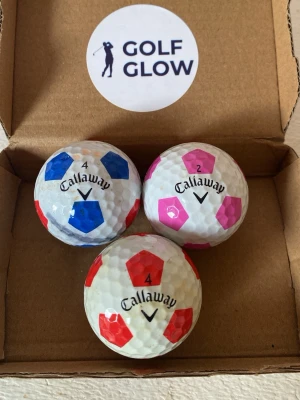 Callaway chromesoft truvis 3-pack - Tre golfbollar från Callaway med unika färgade fält i rosa, blått och svart. Bollarna har ett mönster som påminner om en fotboll och är tillverkade i klassiskt golfbollsmaterial. Perfekta för dig som vill sticka ut på golfbanan.