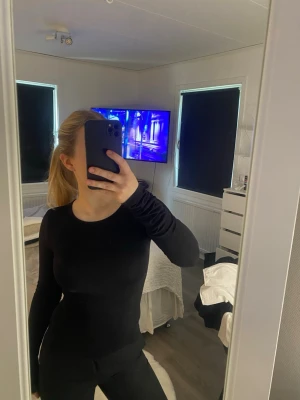 Svart långärmad topp - En enkel och stilren svart långärmad topp med rund halsringning. Tight passform som sitter snyggt på kroppen. Perfekt basplagg att matcha med allt. Materialet känns mjukt och stretchigt.