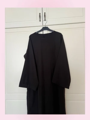 (Abaya) Svart långklänning med lång ärm - En enkel och stilren svart (abaya) långklänning med raka linjer och lång ärm. Klänningen har en rund halsringning och är tillverkad i ett mjukt tyg som faller snyggt. Perfekt för dig som gillar minimalistisk stil. Använd fåtal gånger 💞Har fler abayas om du kollar in i min profil