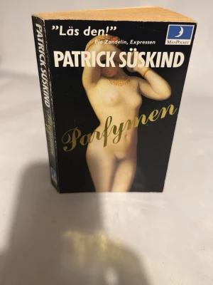 Parfymen av Patrick Süskind - En klassisk pocketbok, 'Parfymen' av Patrick Süskind, utgiven av MånPocket. Omslaget har en konstnärlig bild av en naken kvinna mot svart bakgrund och titeln i guldtext. Perfekt för dig som gillar spännande och mörk skönlitteratur.