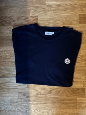 Mörkblå t-shirt från Monkey - Snygg och stilren mörkblå t-shirt från Monkey. Storlek XL på lappen men är närmre  L i verkligheten. Passar dig som bär M även. Liten bit av R:et saknas på baksidan mot urringningen