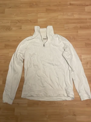 Vit halfzip sweatshirt från Volt magazin  - Vit långärmad sweatshirt från Volt magazin med halv dragkedja och hög krage. Tröjan har en avslappnad passform och är tillverkad i mjukt material, perfekt för en chill och stilren look.