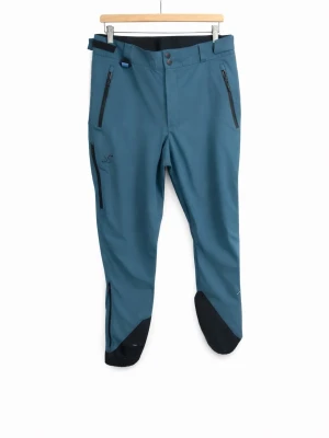 Blå täckbyxor från Revolutionrace  - Snygga blå täckbyxor från Revolutionrace med svarta förstärkningar vid bensluten och dragkedjeförsedda fickor framtill. Byxorna har bälteshällor och är tillverkade i slitstarkt material, perfekta för kalla dagar utomhus.