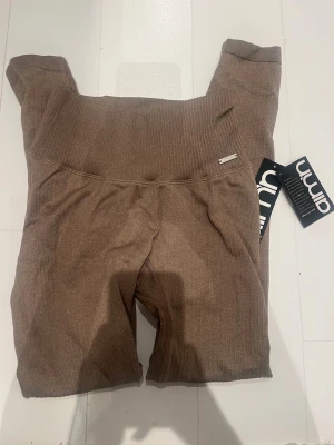 Espressobruna ribbade leggings Aim'n - Snygga ribbade seamless leggings från Aim'n i färgen espresso-brun. Hög midja och stretchigt material som sitter skönt. Perfekta för dig som gillar stilrena och bekväma tights med en trendig vibe. Metallogo framtill och originaltaggar kvar.