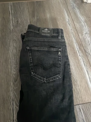 Svarta jeans från Replay - Snygga svarta jeans från Replay med klassisk femficksmodell och diskret logga på bakfickan. Jeansen har raka ben och är tillverkade i ett mjukt denimtyg som ger en bekväm passform. Perfekta för en stilren och avslappnad look.