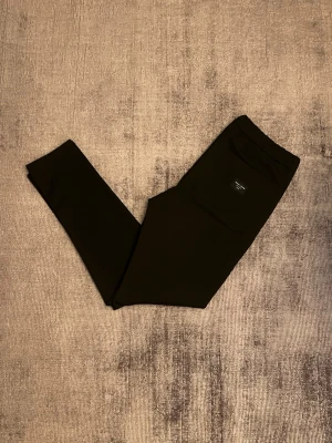 Svarta mjukisbyxor från Replay - Säljer ett par svarta mjukisbyxor från Replay med smal passform och dragsko i midjan. Byxorna har fickor på sidorna och en bakficka med Replay-logga. Perfekta för chill dagar och snygga till sneakers.