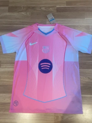 Barça x Nike rosa matchtröja - Snygg rosa och ljusblå FC Barcelona matchtröja från Nike med korta ärmar. Tröjan har klubbmärke, Nike-logga och Spotify-logga på bröstet. Tillverkad i lätt och ventilerande funktionsmaterial, perfekt för fotboll eller träning.