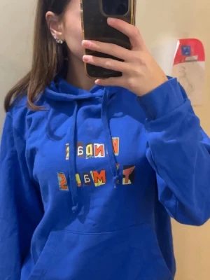 Hov1 Hoodie  - Testar lägga upp den igen. Snygg blå hoodie med huva och dragsko. Framsidan har ett färgglatt tryck med texten ”Vindar På Mars” från ett av Hov1’s album. Köptes på en av deras konsärer. 