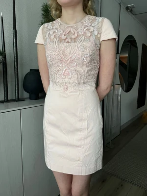 Rosa kort klänning med paljetter från FRENCH CONNECTION - Ändast använd fåtal gånger. En kort kortärmad rosa klänning från FRENCH CONECTION