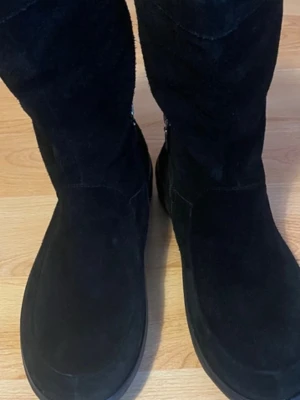 Svarta mockastövlar från FitFlop - Säljer ett par svarta stövlar från FitFlop i mjuk mocka med diskret dragkedja på sidan. De har en rundad tå och en bekväm, något tjockare sula som ger bra stöd. Perfekta för kalla dagar och passar till många olika outfits. Super dämpande sulor!!! Ska passa st. 40,5-41. 