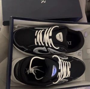 Dior B30 svarta sneakers med silverdetaljer - Säljer ett par Dior B30 sneakers i svart med silvriga detaljer och vit sula. Bästa priserna här på Plick och skicka gärna in bud då jag kan sänka priset vid snabb affär.