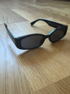 Svarta solglasögon från H&M - Snygga svarta solglasögon från H&M med rektangulära bågar och mörka glas. Perfekt accessoar för att lyfta din stil under soliga dagar. Klassisk design som passar till det mesta. Aldrig använda.