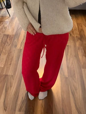 Röda mjuka loungewear-byxor - Säljer ett par röda loungewear-byxor med avslappnad passform och dragsko i midjan. Byxorna är tillverkade i ett mjukt och bekvämt material, perfekta för hemmamys eller chill dagar. Färgen är klar röd och modellen har raka ben.