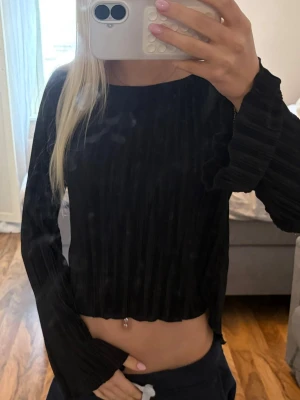 Svart ribbad  - Säljer en svart croppad topp med långa ärmar och ribbad struktur. Toppen har en enkel, stilren design och är perfekt för dig som gillar en trendig och bekväm look. Materialet känns mjukt och följsamt mot kroppen.