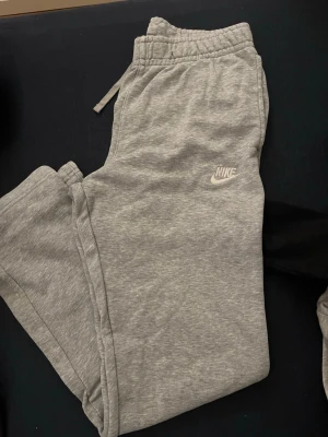 Gråa mjukisbyxor från Nike - Snygga grå mjukisbyxor från Nike med klassisk logga på benet, tillverkade i mjukt och bekvämt material.