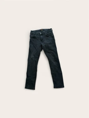 Lee Jeans "Daren Zip Fly" (W30/L32) – Regular Fit - Säljer ett par snygga märkesjeans från Lee i den populära modellen "Daren". Passformen är Regular Straight, vilket innebär normalhög midja och raka ben. En klassisk passform som varken sitter för tajt eller för löst.  Färgen är en snygg mörkgrå/tvättad svart nyans som funkar till både t-shirt och skjorta. Skick: Mycket fint skick! Inga slitningar i grenen eller nertill vid fötterna. Färgen är fortfarande fin. Storlek: W30 / L32 (Midja 30, Längd 32). Nypris ca 1200 kr.