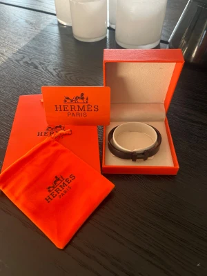 Svart läderarmband från Hermès - Snyggt svart armband från Hermès i läder med metallspänne. Kommer i original orange ask och tygpåse med Hermès-logga. Perfekt accessoar för dig som gillar stilrena och exklusiva detaljer.