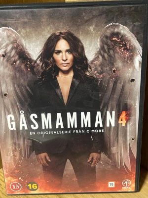 Gåsmamman Säsong 4 DVD-box - DVD-box med fjärde säsongen av serien Gåsmamman från C More. Omslaget är mörkt med en person i svart kostym och stora vingar i bakgrunden. Text på svenska, danska och finska på baksidan. Rekommenderad ålder 15/16 år. Perfekt för dig som gillar spänning och drama.