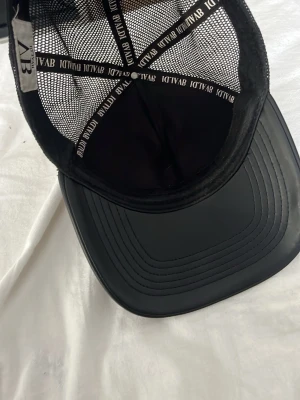 Svart keps från BVALDI med mesh - Snygg svart keps från BVALDI med mesh på sidorna och bak. Framtill finns två broderade tigrar och BVALDI-loggan i vitt. Skärmen är böjd och materialet är en mix av tyg och mesh för en luftig känsla. Perfekt för en streetwear-look. Skick 8/10 Inga fläckar eller hål. OBS Kepsen går inte att köpa ifrån bvaldi längre