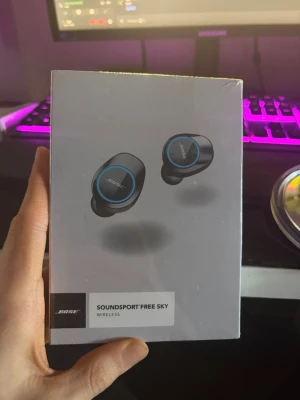 Bose Soundsport Free Sky trådlösa in-ear - Snygga svarta trådlösa in-ear-hörlurar från Bose, modell Soundsport Free Sky. Hörlurarna har blå detaljer och levereras i ett smidigt laddningsetui. Perfekta för musik, gaming eller träning tack vare stabil passform och Bluetooth-anslutning.