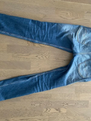 Blå replay Jeans med slim fit jeans med slitningar - Snygga blå slim fit jeans med slitningar och tvättade detaljer. Klassisk femficksmodell med normal midja och smala ben. Jeansen har kontrastsömmar och är tillverkade i denim, vilket ger en cool och avslappnad look.