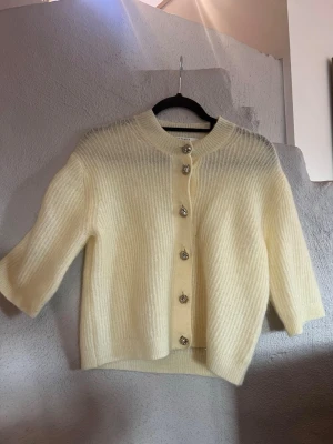 Kortärmad ull-cardigan  - Second Female - Andria Knit Cardigan Koftan är väldigt mjuk, ljust gul och mestadels ull och mohair UII - 34% Mohair (angora) - 34% Nylon - 27% och Elastan 5% Koftan är helt oanvänd men saknar lapp Normal i storleken  Nypris - 2200kr