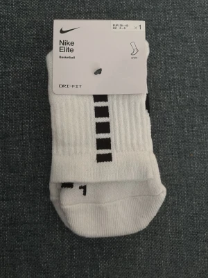 Nike Elite vita basketstrumpor - Nike Elite basketstrumpor i vitt med svarta detaljer och randigt mönster. Strumporna är i ett mjukt och funktionellt material med Dri-FIT-teknologi som håller fötterna torra. Möts helst för att göra de lättare 