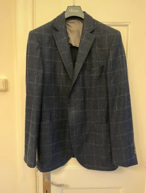 Mörkblå kavaj från Eduard Dressler  - Oerhört snygg marinblå kavaj från Eduard Dressler med diskret rutmönster i vitt. Klassisk passform med två framfickor och bröstficka. Tillverkad i ett mjukt tyg av bland annat Kashmir och silke. Nypris ligger på 7000kr, kom med bud!