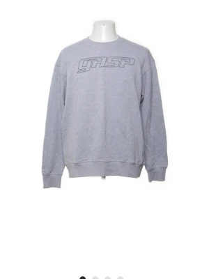Grå sweatshirt från GASP - Snygg grå sweatshirt från GASP med tryckt logga framtill och liten logga i nacken. Tröjan har rund hals, ribbade muddar vid ärmslut och nederkant samt en avslappnad passform. Perfekt som pumpcover på gymmet eller till vardags. 