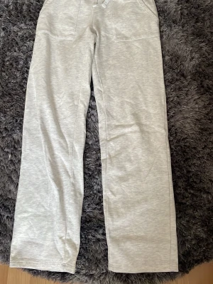 Ljusgrå mjukisbyxor med raka ben - Säljer ett par ljusgrå mjukisbyxor med raka ben och resår i midjan. Byxorna har stora fickor både fram och bak och är gjorda i mjukt sweatshirtmaterial.